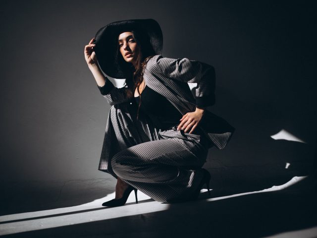 Woman model in a business suit wearing a hat in a studio